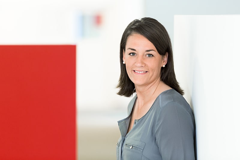 Mitarbeiterin bei Schröter GmbH, Experten für C-Artikel-Beschaffung und E-Procurement-Lösungen, steht lächelnd da.