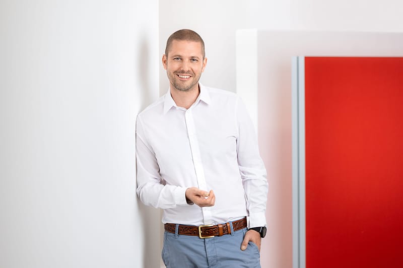Mitarbeiter in einem weißen Hemd steht an einer Wand, repräsentiert Schröter GmbH, Spezialist für C-Artikel-Beschaffung.