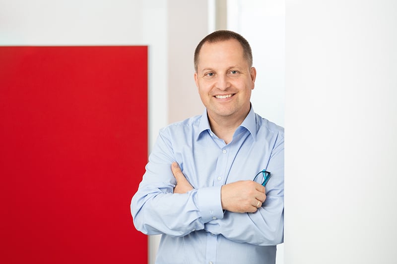 Mitarbeiter lächelt in modernem Büro der Schröter GmbH, Experten für C-Artikel-Beschaffung und E-Procurement.