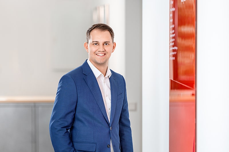 Mitarbeiter von Schröter in einem blauen Anzug steht in einem modernen Büro von Schröter GmbH für C-Artikel-Management.