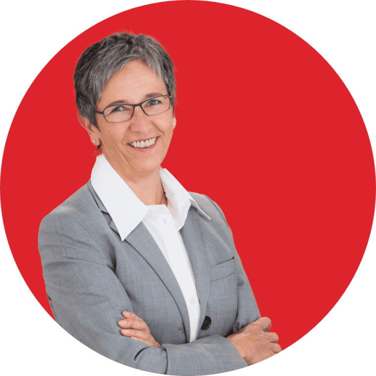 Frau im Anzug vor rotem Hintergrund, repräsentiert Schröter GmbH, ein familiengeführtes Unternehmen für C-Artikel-Management.