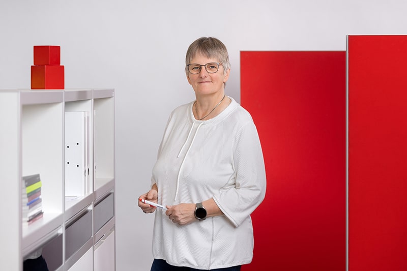 Mitarbeiterin in Büro mit weißen und roten Akzenten, repräsentiert die Schröter GmbH und ihre C-Artikel-Management-Lösungen.